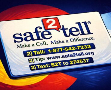 A high school hallway with a police officer talking to an administrator near lockers